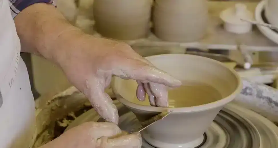 Theepot van keramiek op de draaischijf naar boven werken op de rand