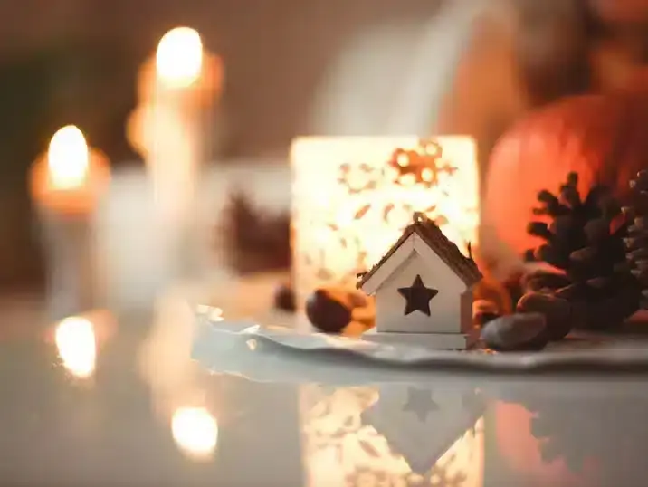 Een detail van een keramieken huisje in een herfstige setting met kaarslicht