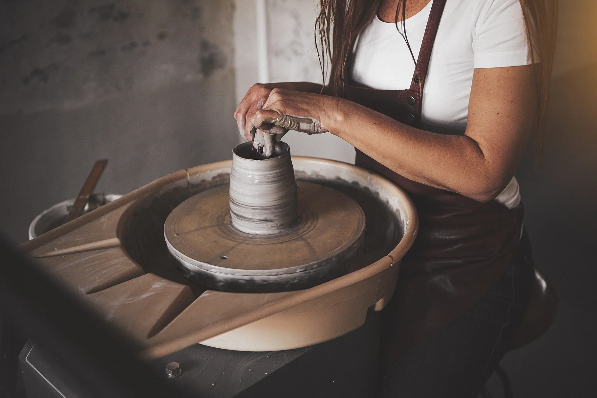 Klei mengen: keramiste aan draaischijf draait pot met gemengde klei
