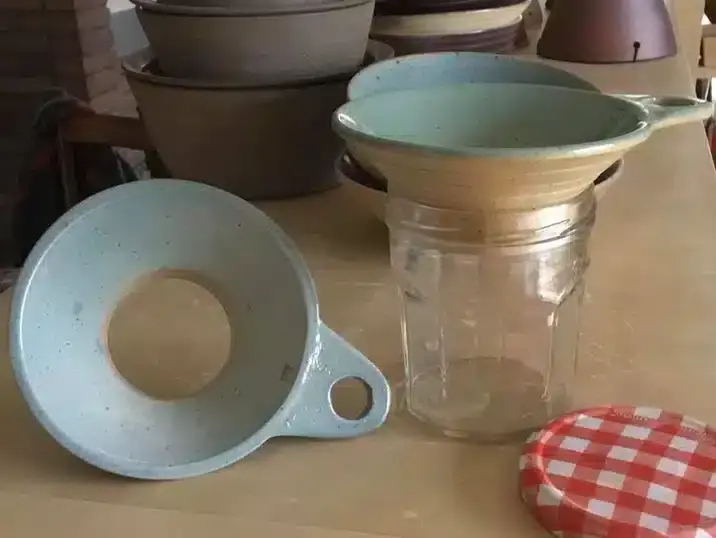 Twee confituur trechters gemaakt van klei bij een glazen bokaal en metalen deksel