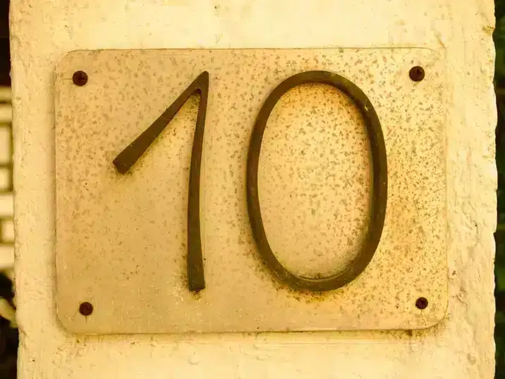 Het huisnummer tien op een gele muur