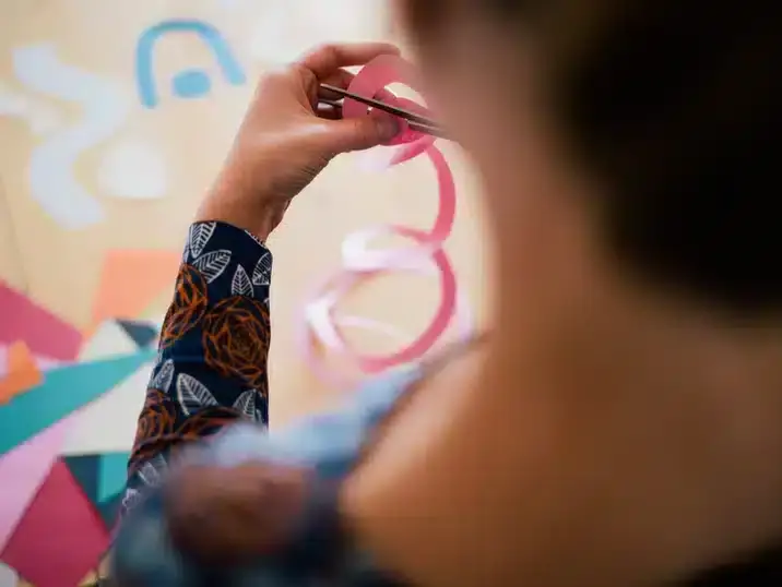 Iemand knipt met een schaar vormen uit roos papier