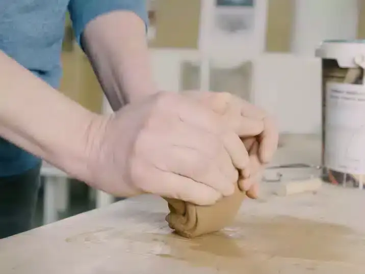 Een detail van de handen van cursist docent Françoise Busin die klei kneden