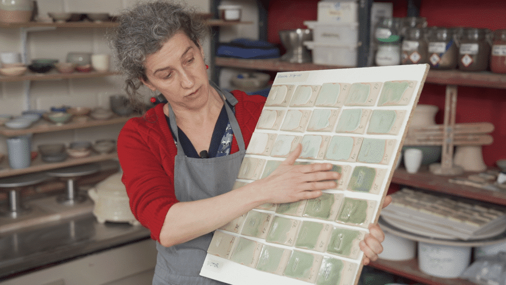 Caroline Kestelyn in haar atelier met testplaatjes geglazuurde keramiek volgens de grid methode in de cursus glazuren