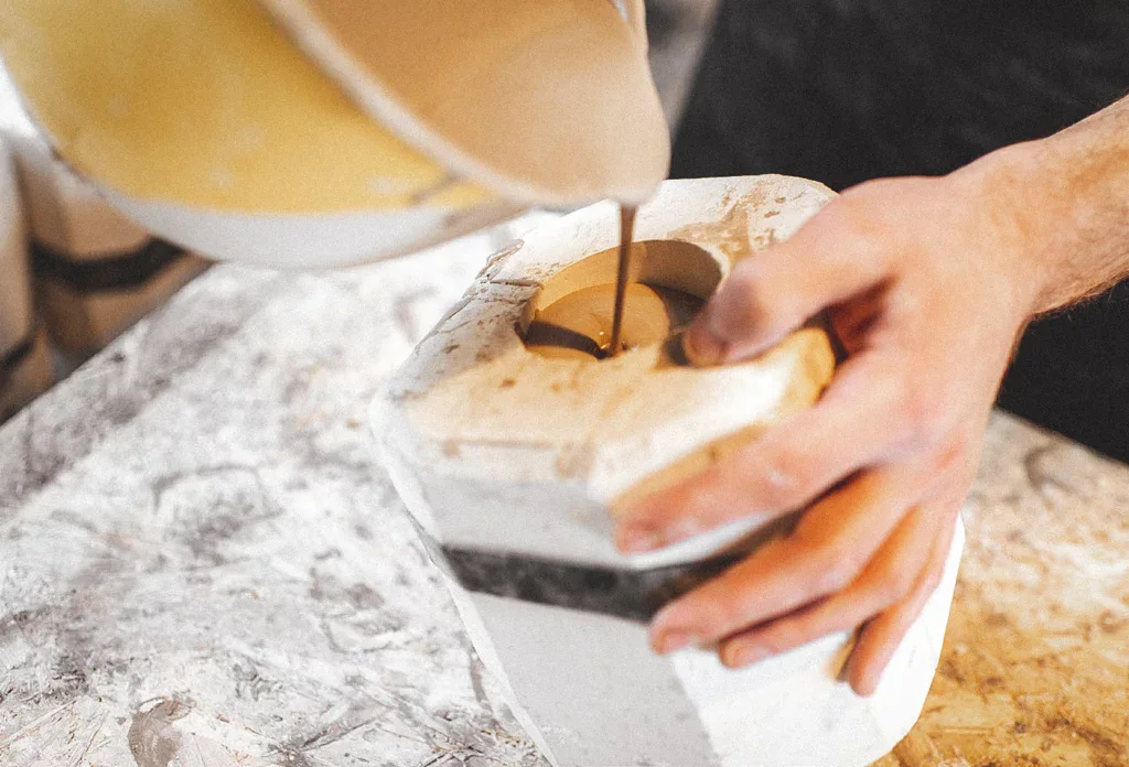 Pottenbakken benodigdheden: man giet klei in gietmal