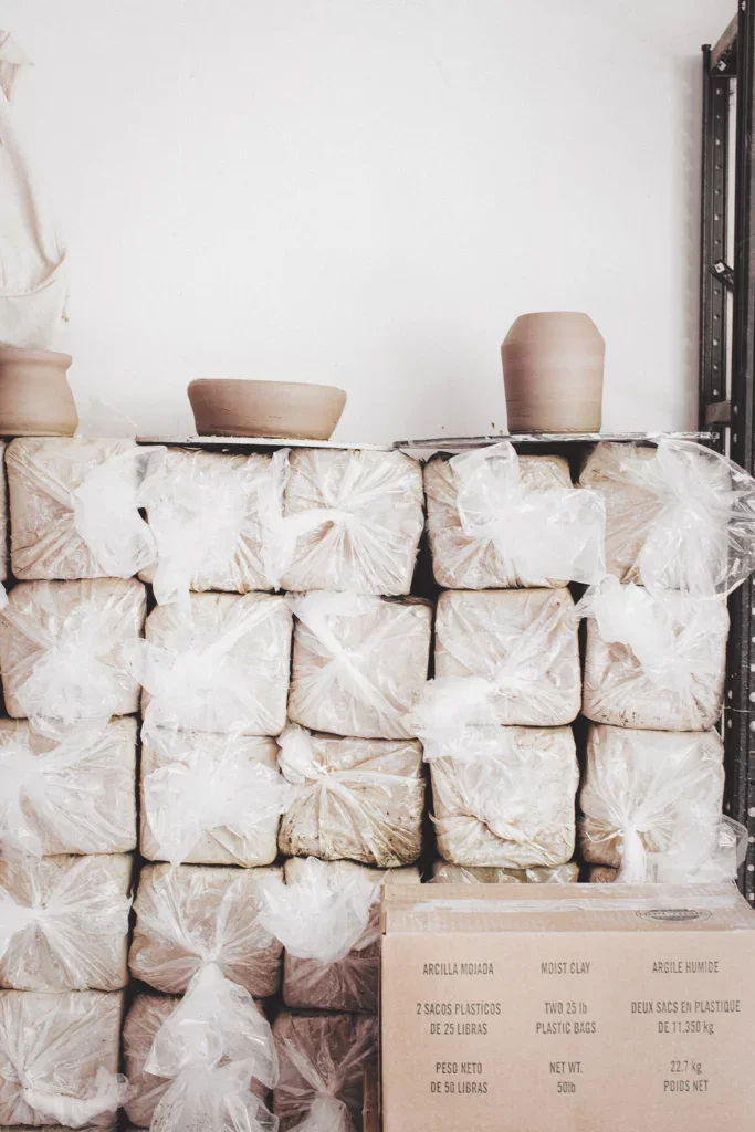 een hele hoop pakken klei op een stapen in het atelier