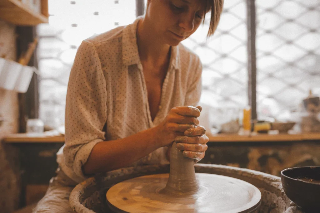 Vrouw die klei aan het centreren is op de draaischijf