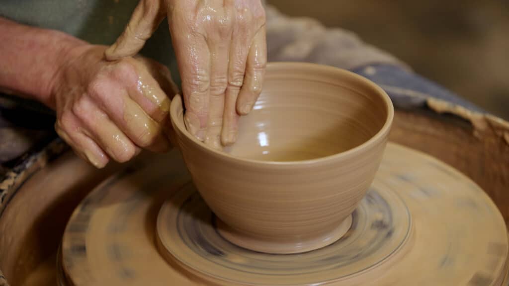 Handen van Aster Caemaert op een kom tijdens de cursus pottenbakken