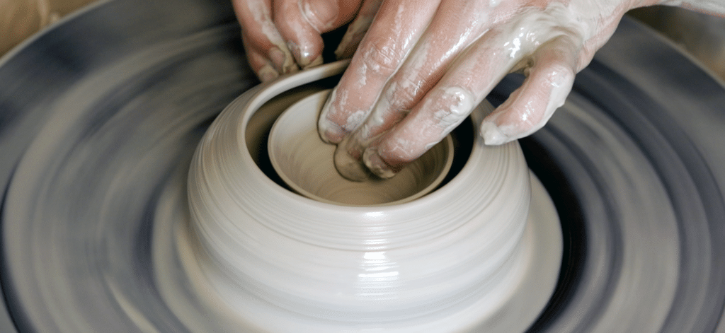 Gesloten vormen draaien: handen op gesloten vorm op de draaischijf