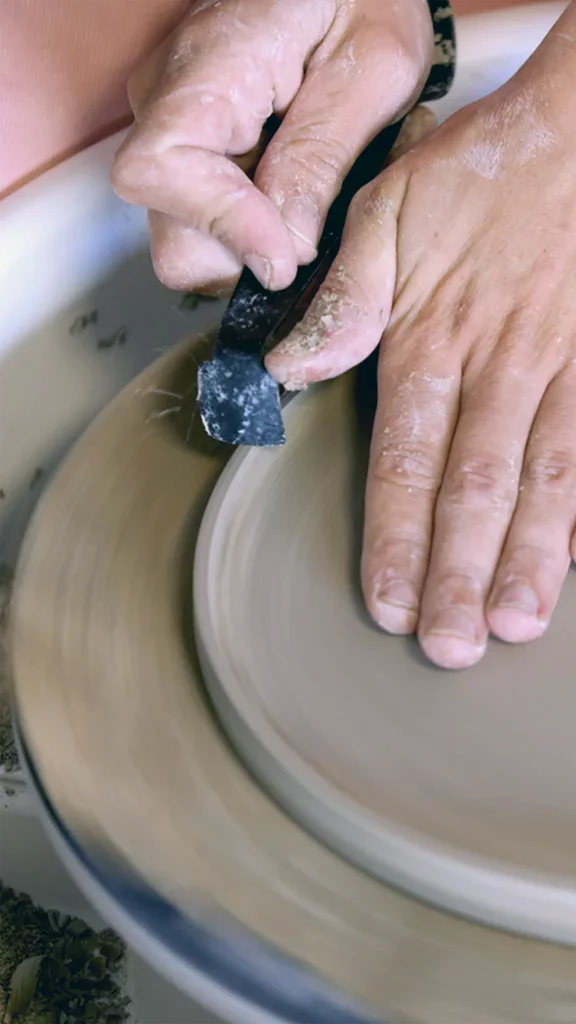 Keramiek taartplateau: handen van Sofie De Cleene trimmen een bord van een plateau apéro