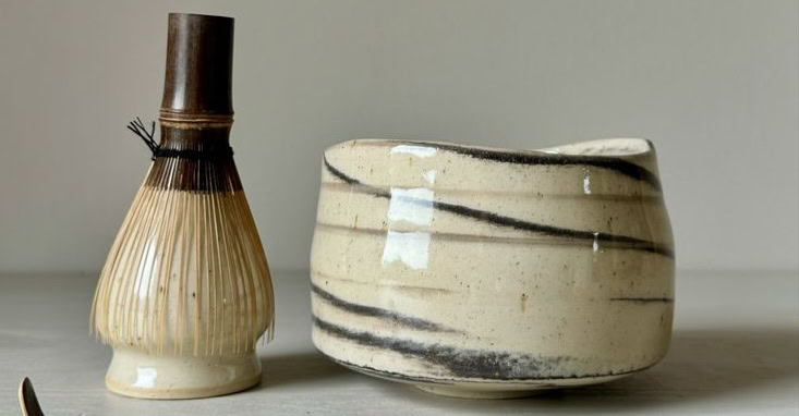 De chawan in keramiek voor matcha in het beige met zwarte strepen en bamboe garde