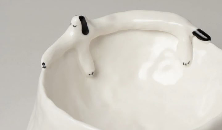 De voerbak in keramiek in het wit met een hondje van porselein